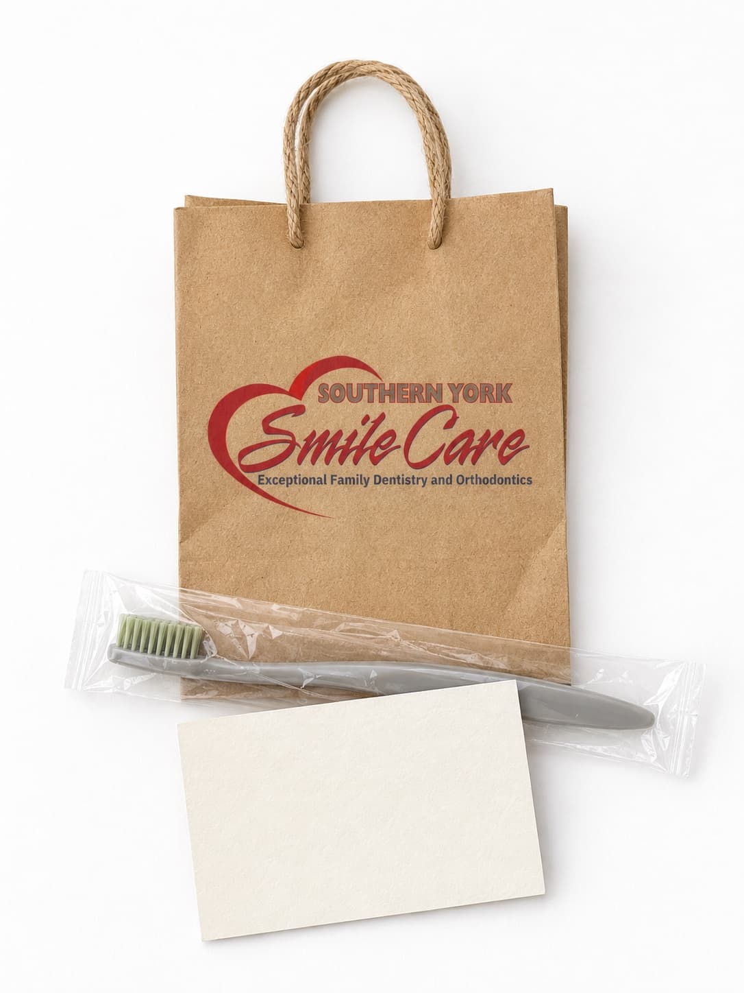 A Southern York Smile Care kraft aftercare bag with a toothbrush and appointment card