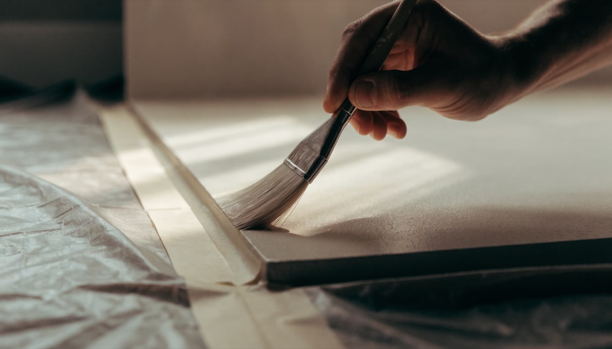 Close crop of a painter cutting a crisp line along a ceiling edge