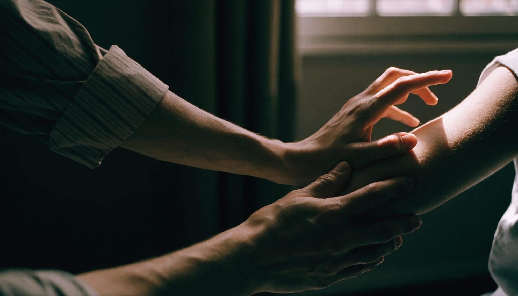 A physiotherapist's hands guiding a patient through a shoulder movement