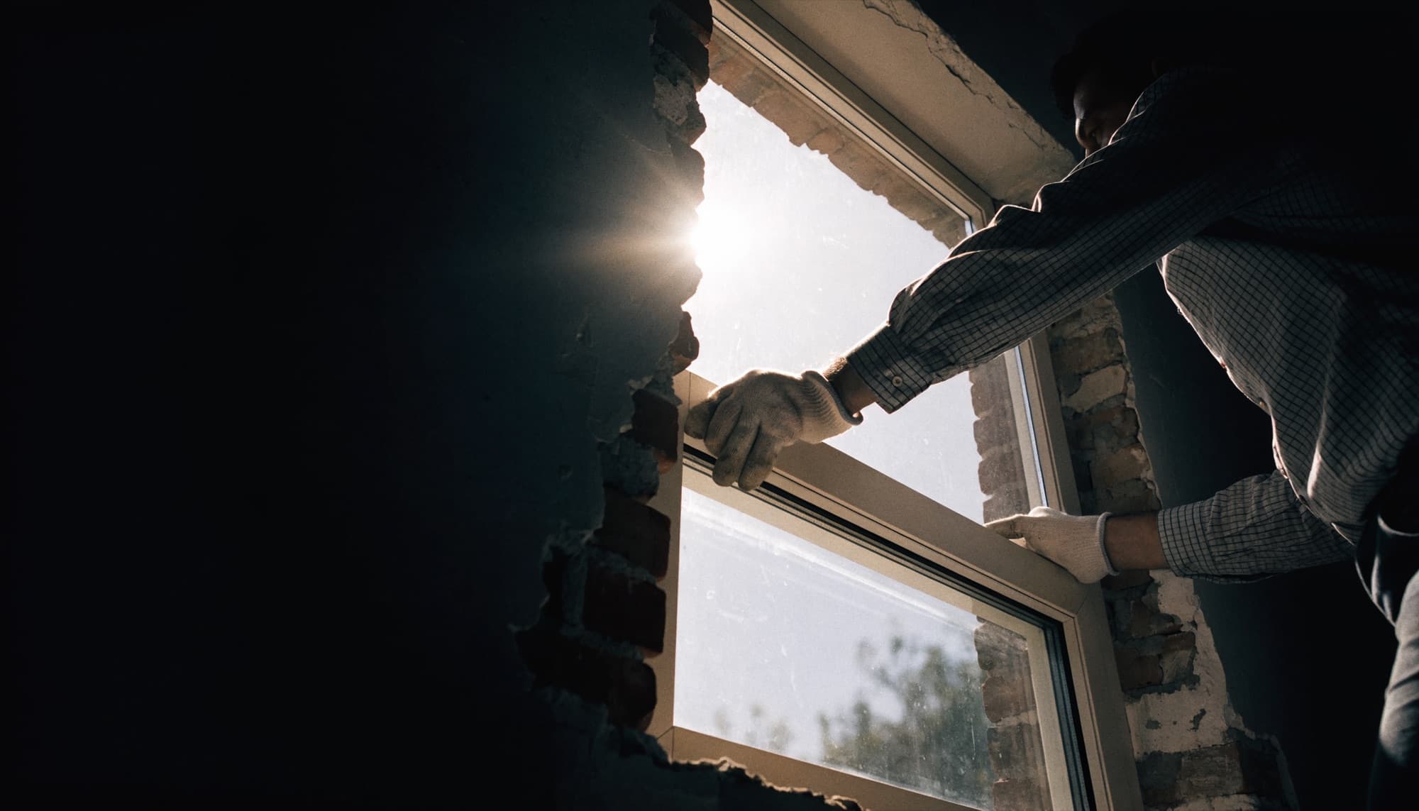 An installer setting a large window unit into a rough opening